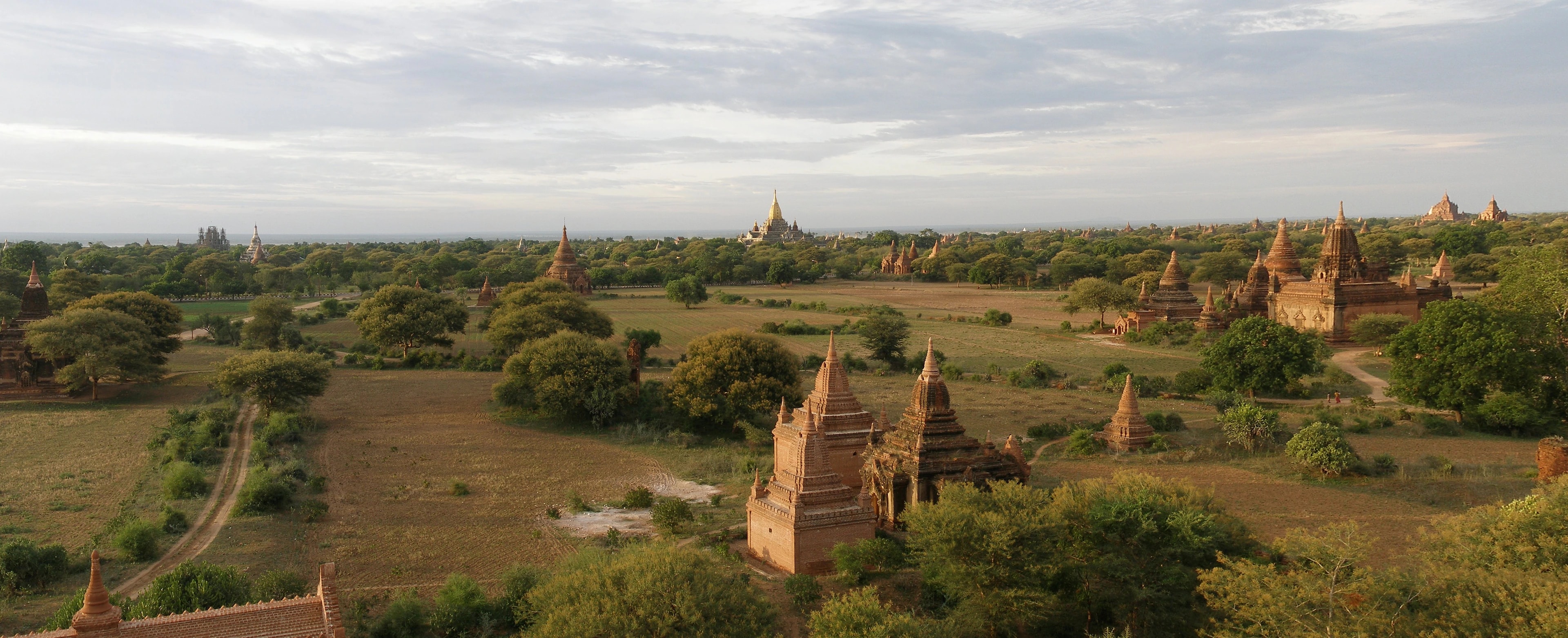Sunlit brick temples and golden pagodas across the green plains of Bagan